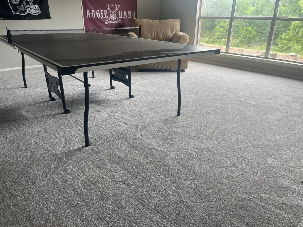 The same game room with new grey carpet beneath the ping-pong table