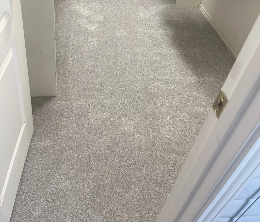 The same walk-in closet with new grey carpet, seen through the open doorway