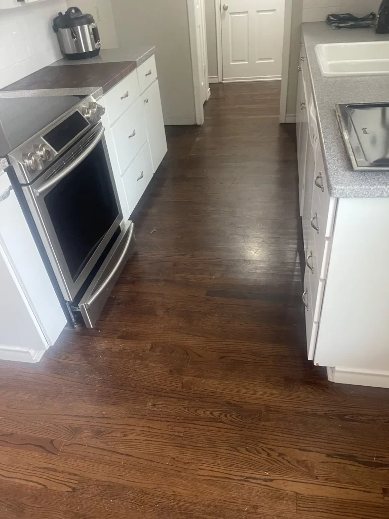 Galley kitchen with the original dark stained strip oak floor, worn and scuffed along the walkway