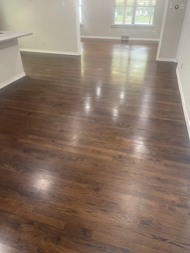 Living room with dark strip oak flooring in a glossy finish before replacement