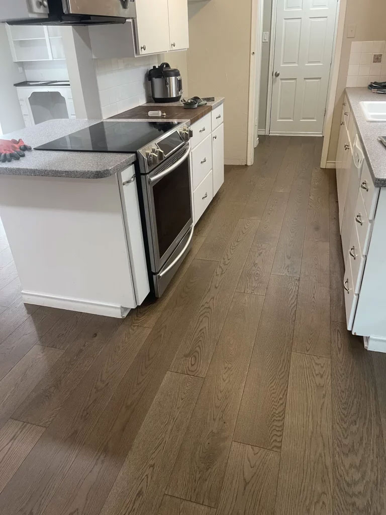 The same galley kitchen with a light wide-plank white oak floor running toward the doorway
